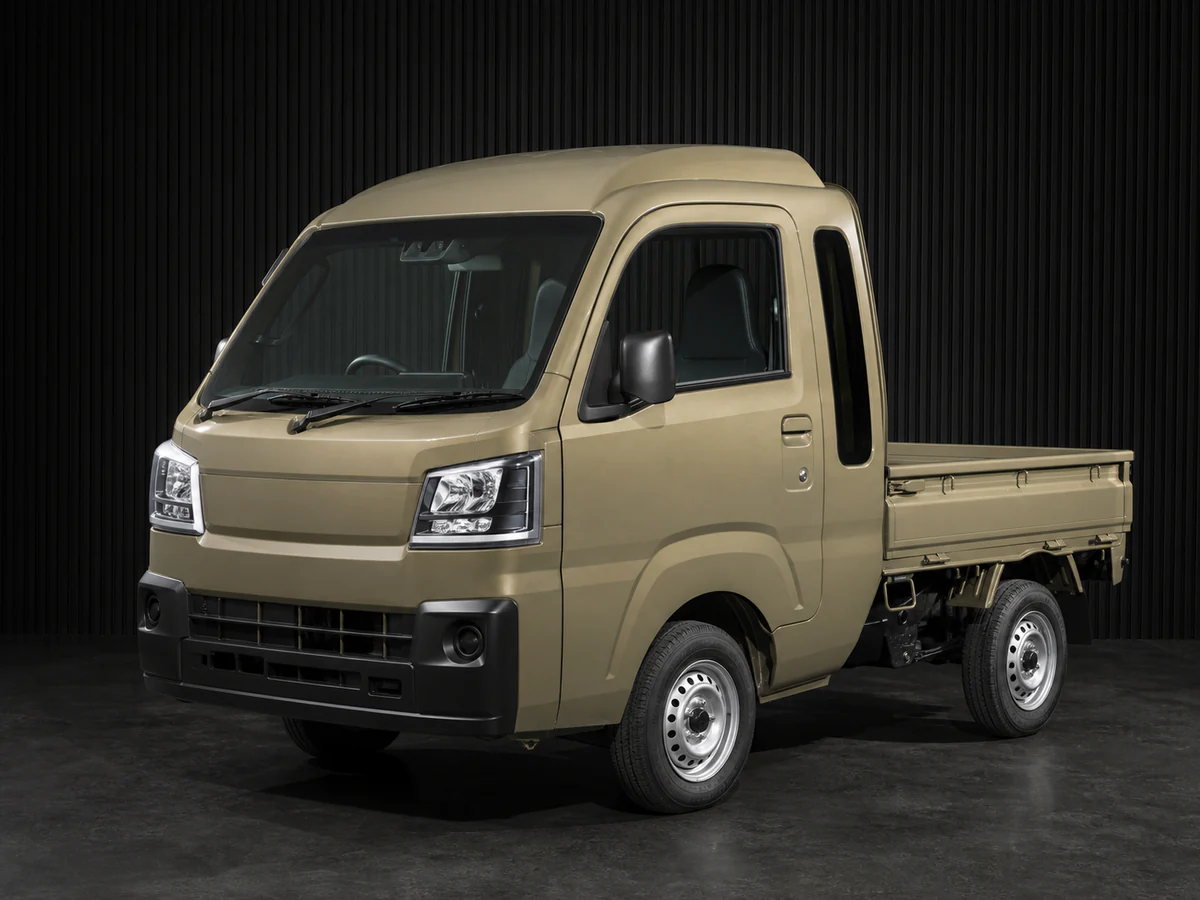 Current khaki Daihatsu Hijet S510P-style Jumbo kei truck in a dark grooved-wall studio