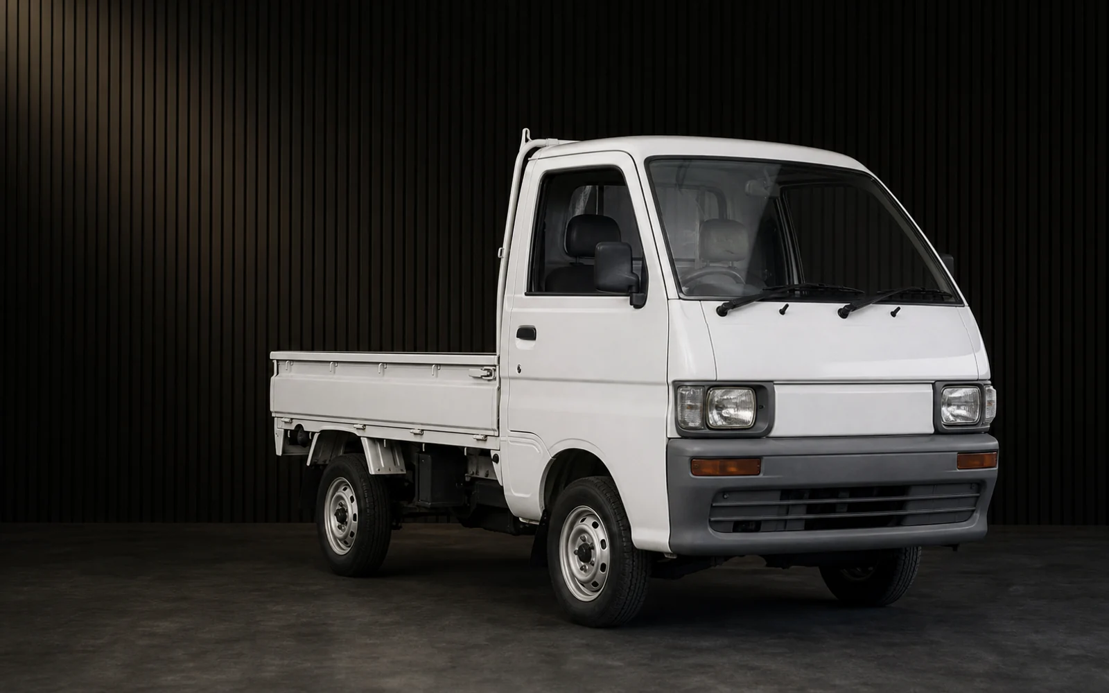 1990s Daihatsu Hijet S110P-era 4WD kei truck in a dark grooved-wall studio