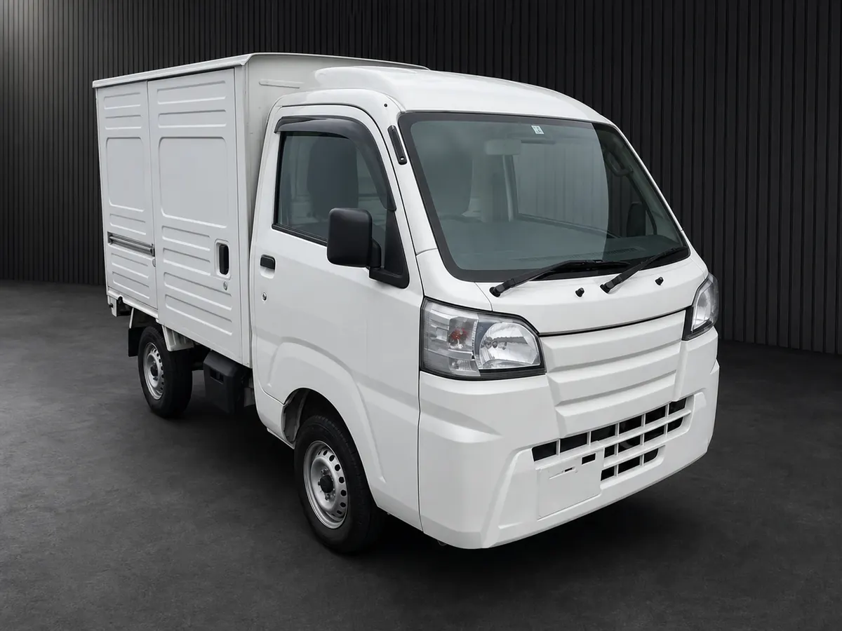 Front three-quarter view of a white kei truck with a tall ribbed enclosed cargo box
