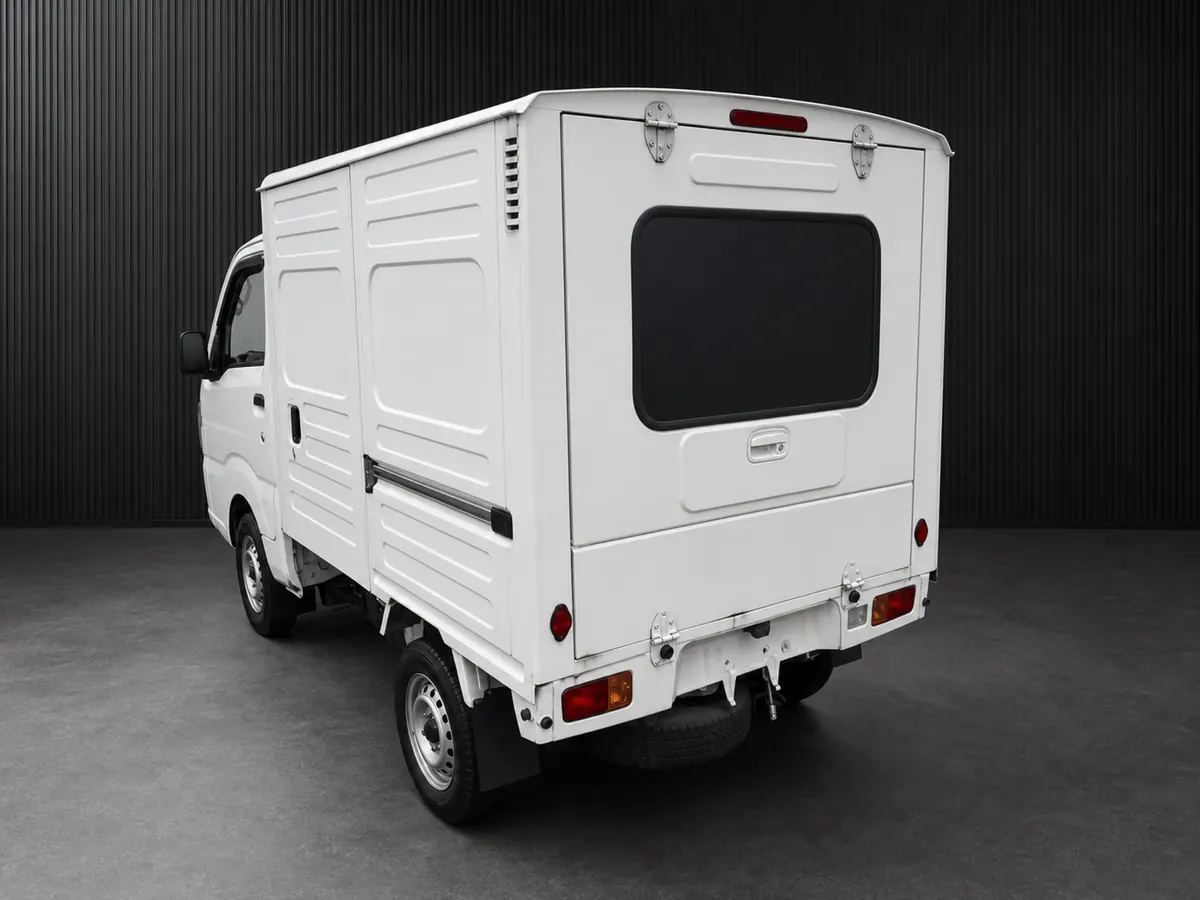 Rear three-quarter view of a white kei truck with a ribbed enclosed cargo box