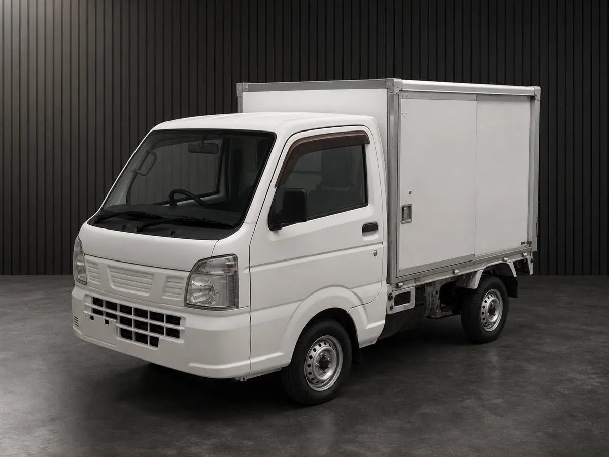 Front three-quarter view of an older white kei truck with a smooth enclosed cargo box