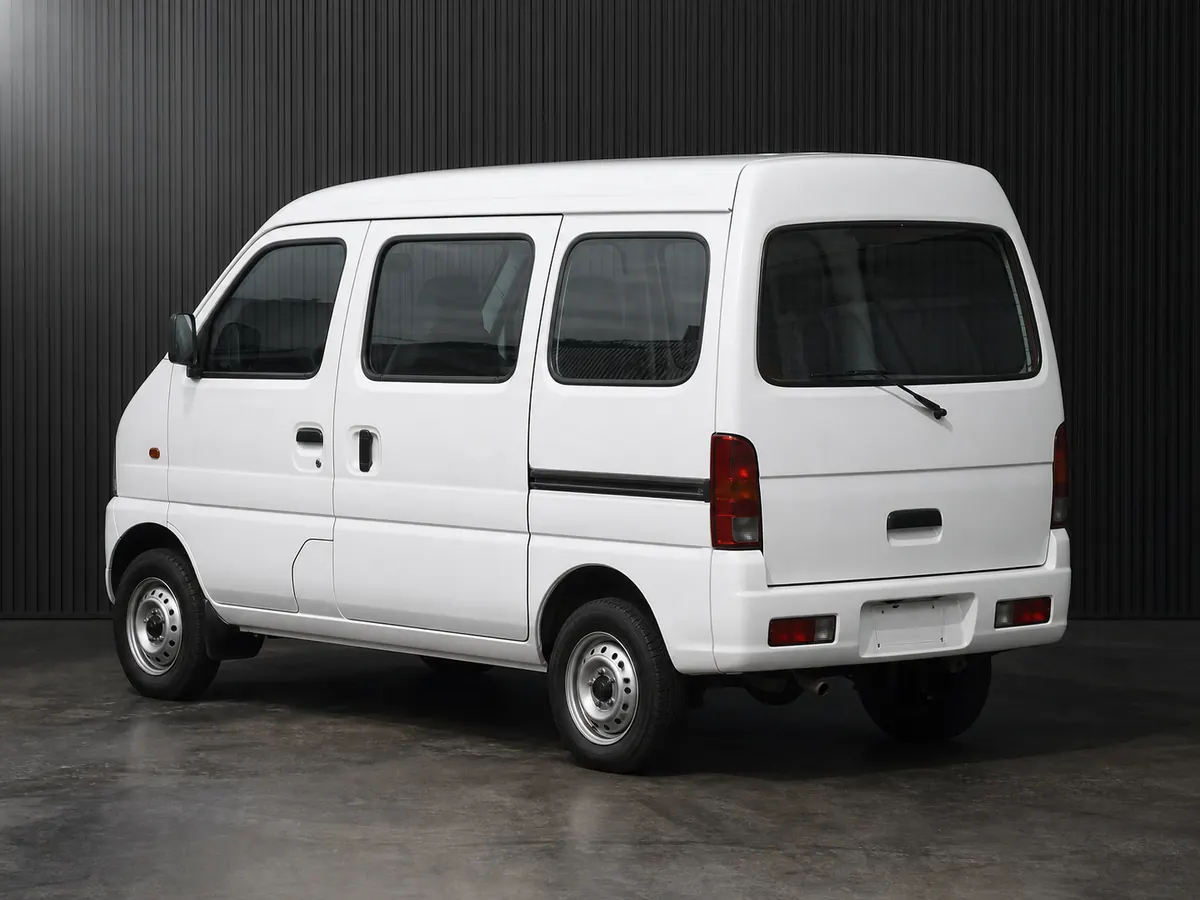 White late-1990s Suzuki Every-style commercial cargo kei van in a grooved-wall studio